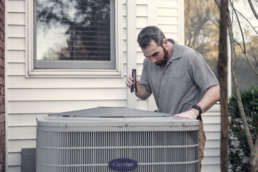 A technician working on an outdoor heating unit